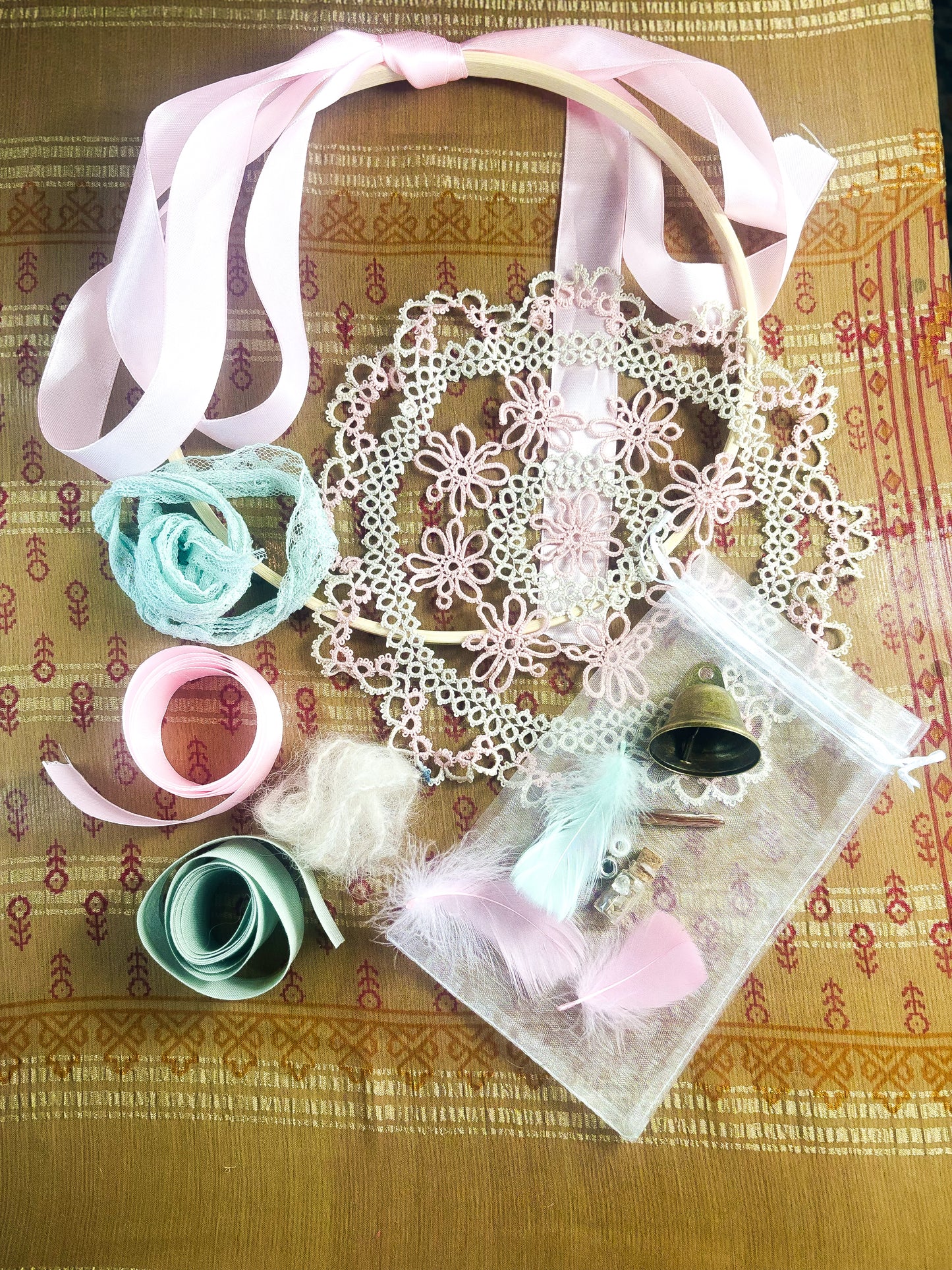 Decorative items including ribbons, doilies, and flowers on a patterned fabric background