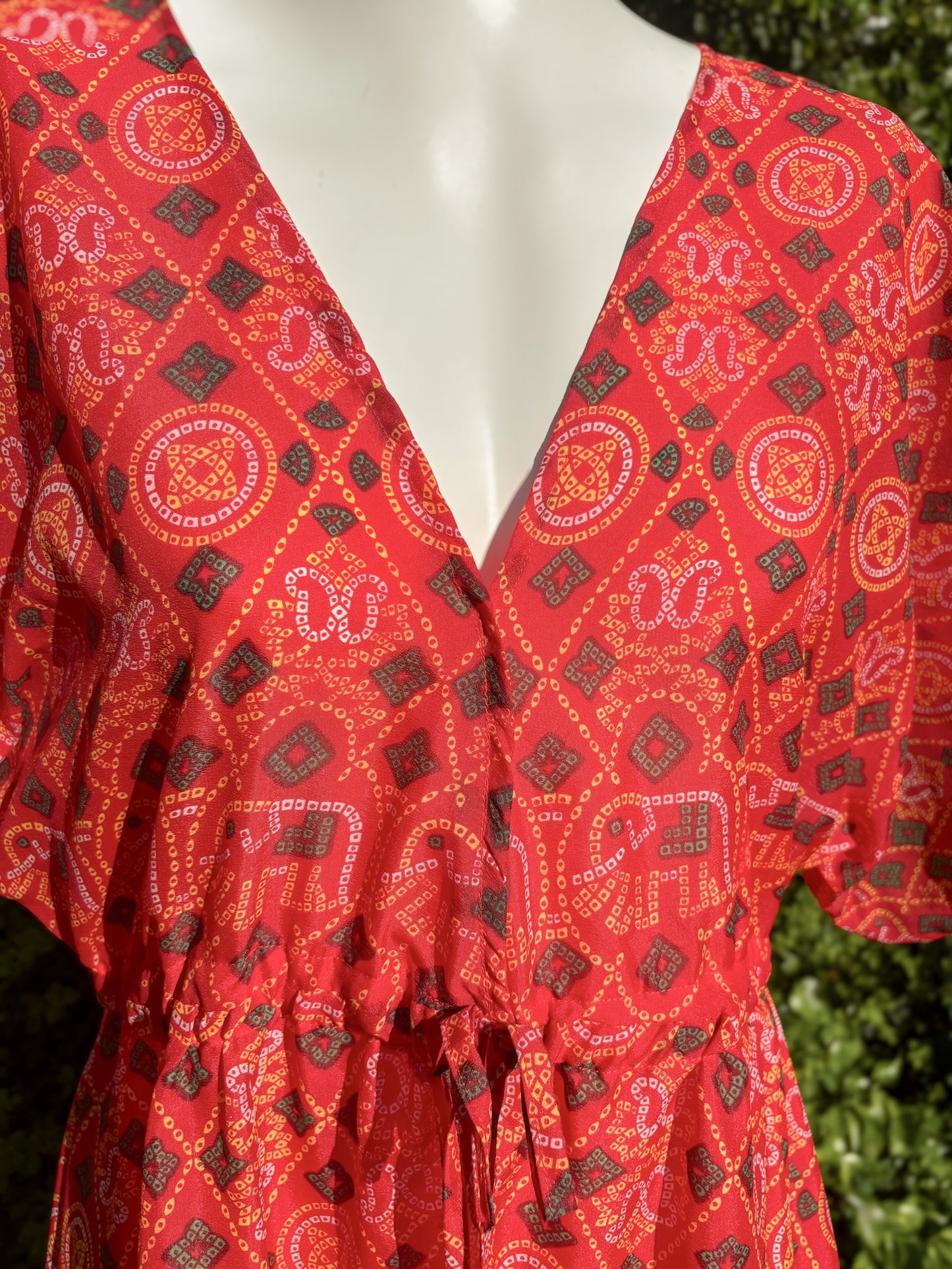 Red patterned dress on a mannequin with a blurred green background