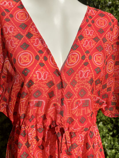 Red patterned dress on a mannequin with a blurred green background