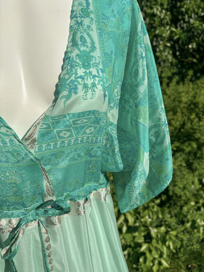 Teal patterned dress on a mannequin with a blurred green outdoor background