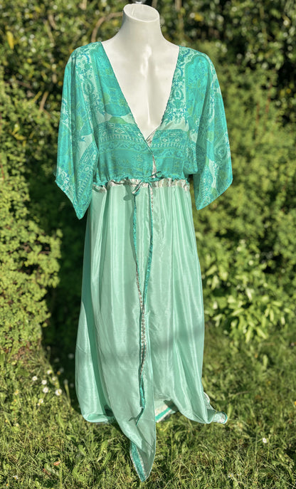 Teal lace dress on a mannequin against a green foliage background
