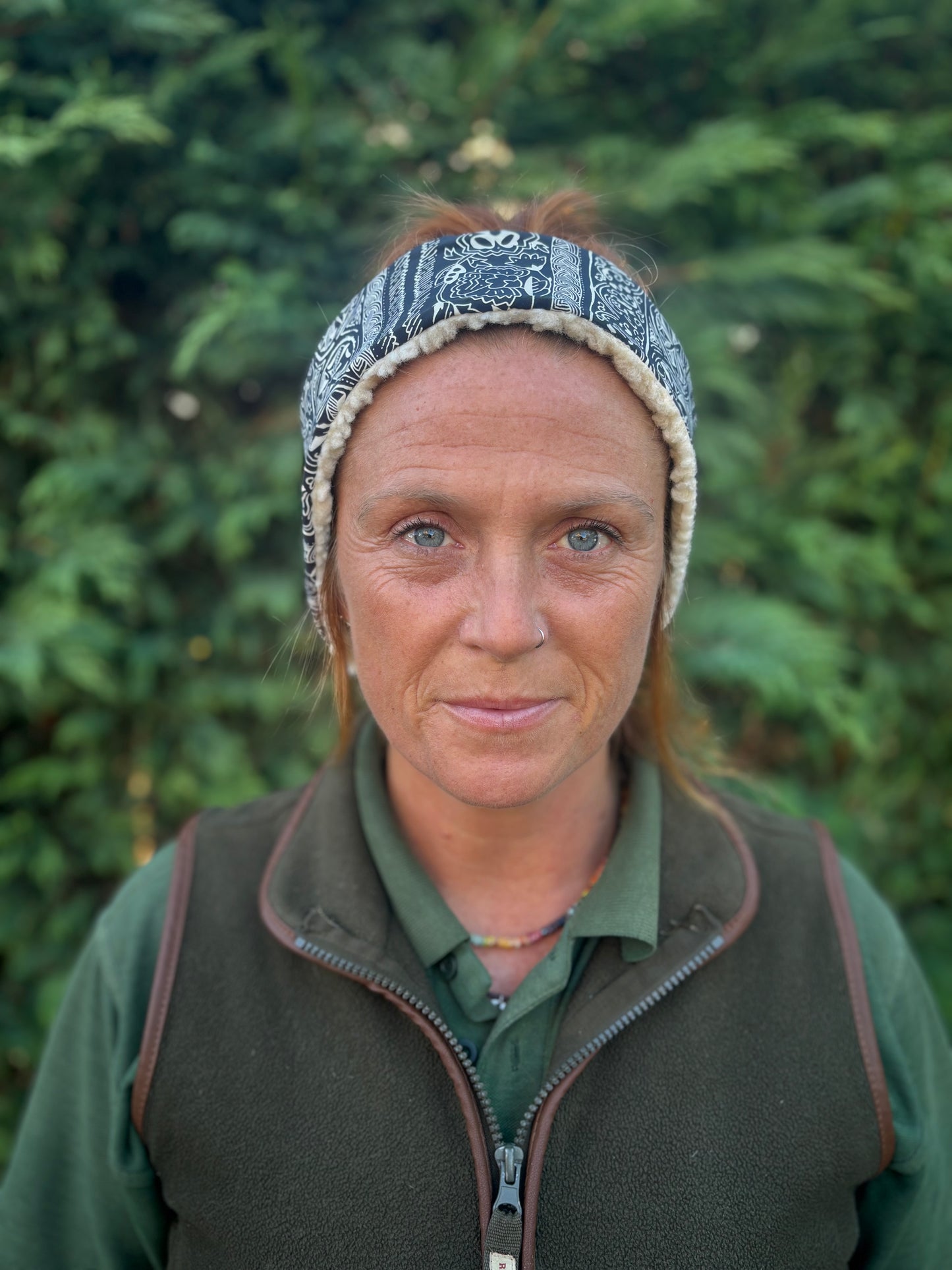 Person wearing a headband and green jacket against a blurred green background