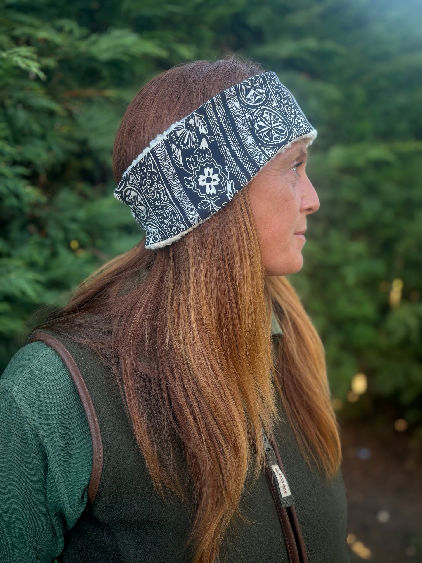 Woman wearing a patterned headband with trees in the background