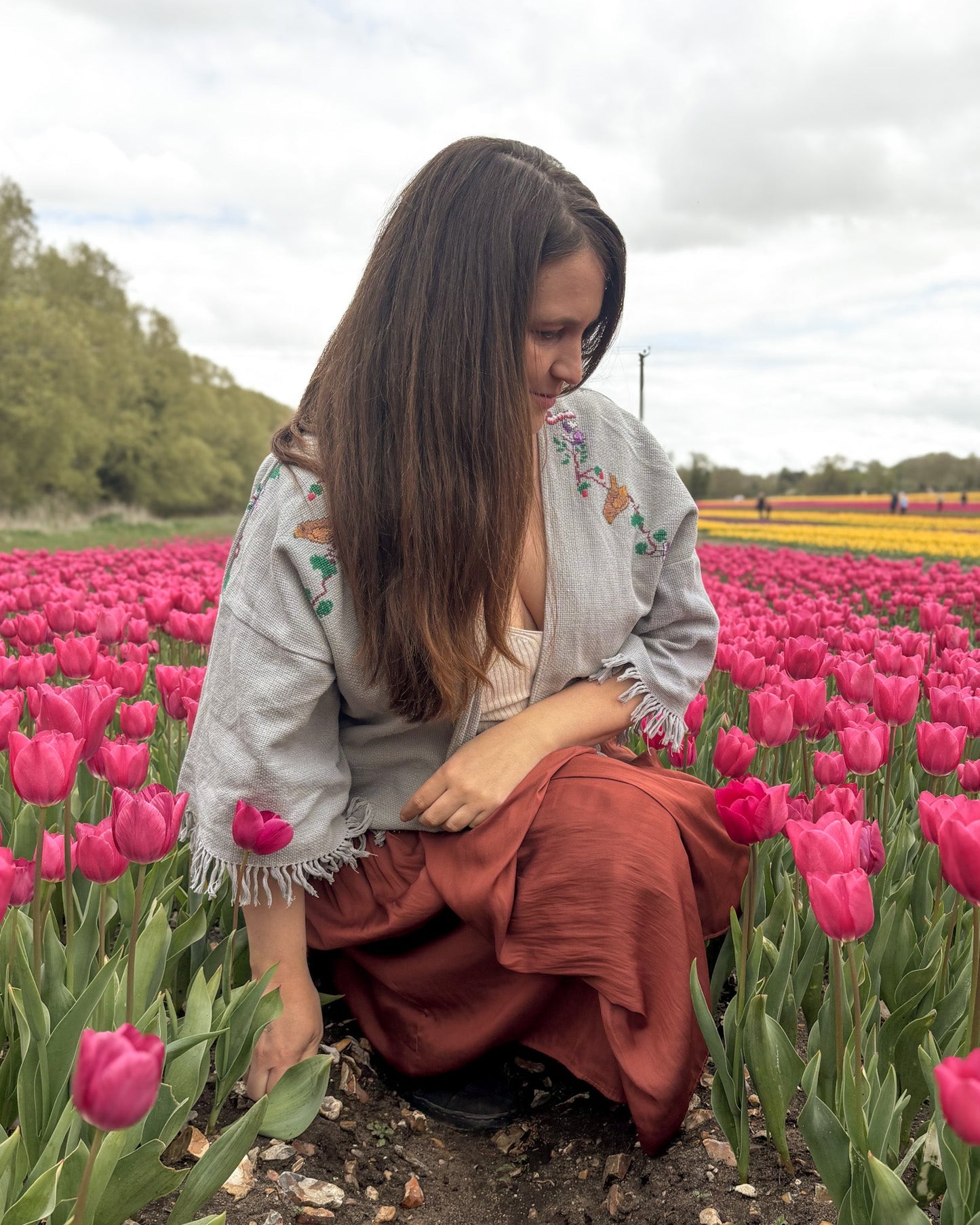 Woman sitting in a field of pink tulips with a blurred background