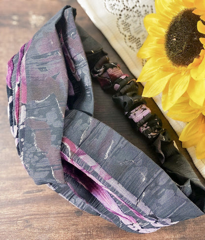 Gray patterned fabric with pink accents on a wooden surface next to a sunflower.