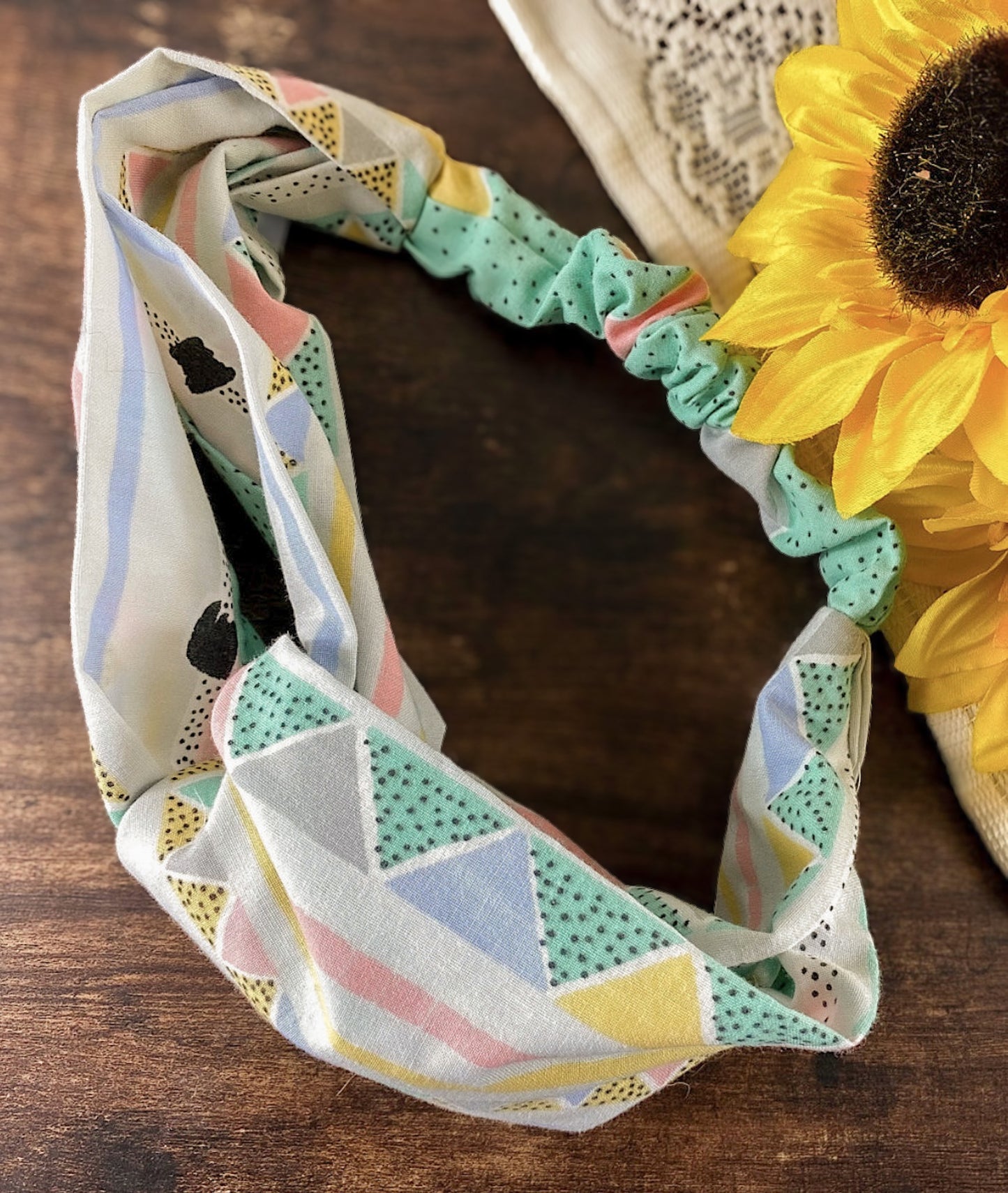 Colorful geometric-patterned headband on a wooden surface with a sunflower in the background