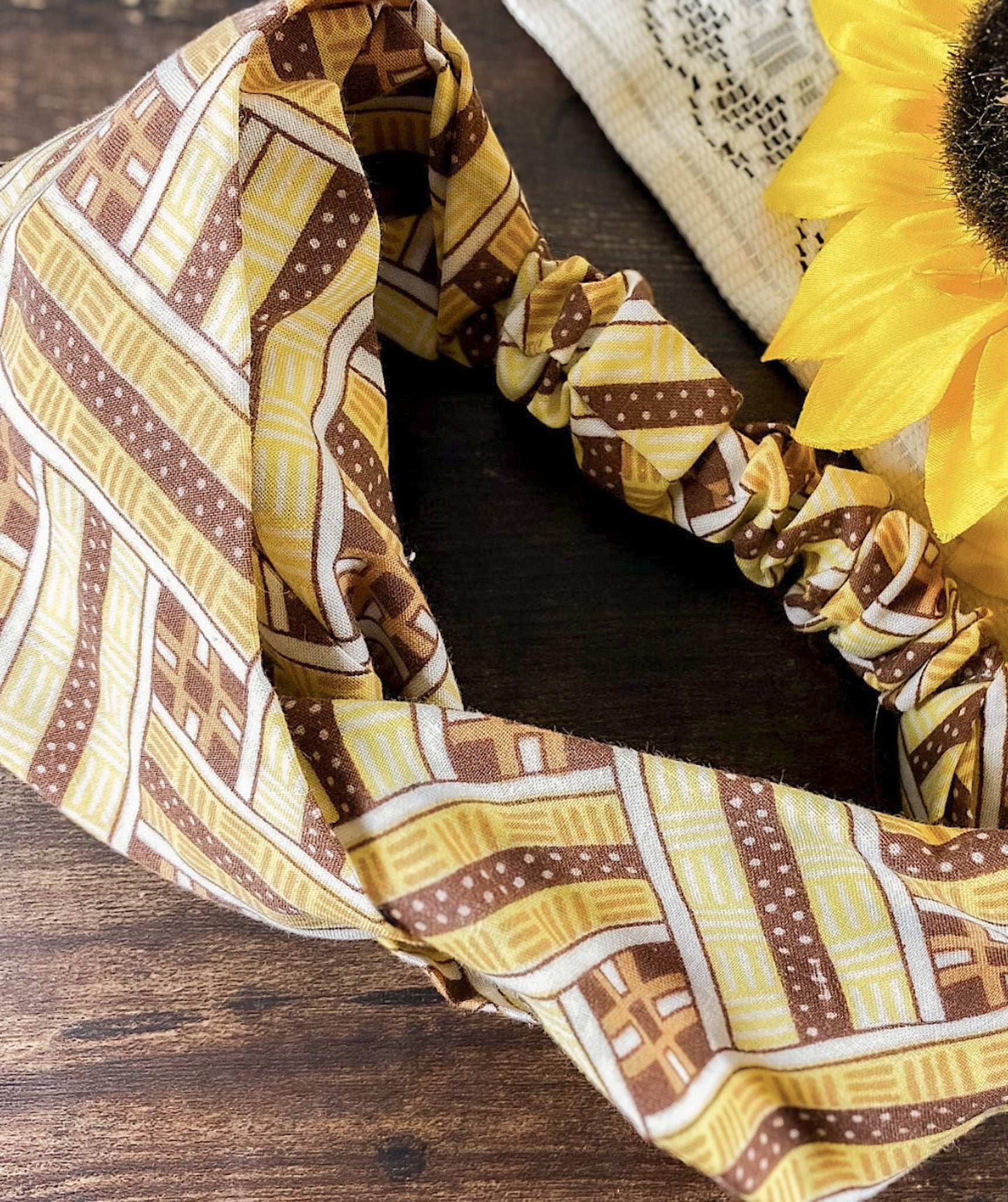 Patterned headband on a wooden surface with a sunflower