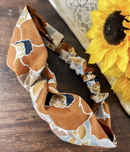 Floral patterned headband on a wooden surface with a sunflower in the background
