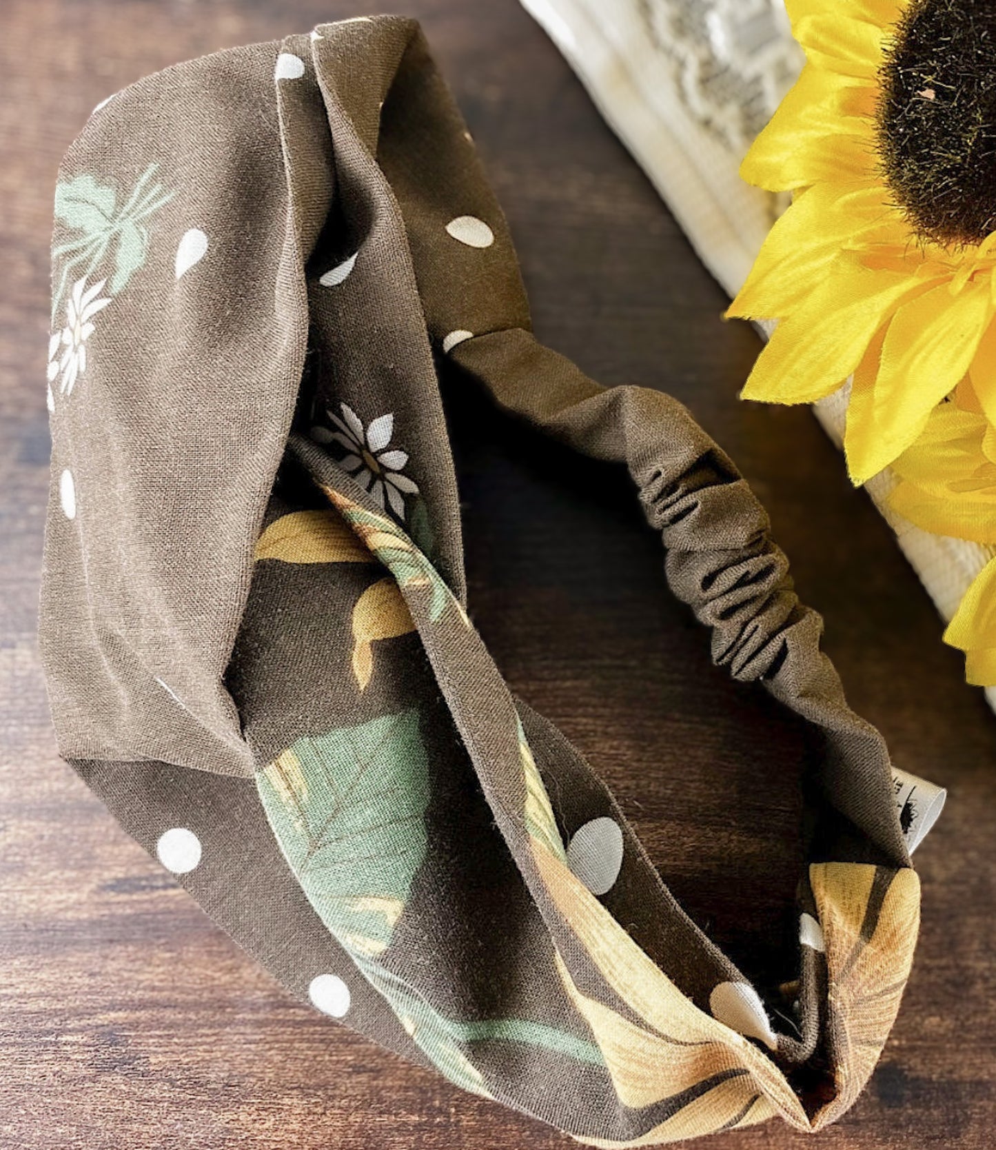 Floral patterned headband on a wooden surface with a sunflower in the background