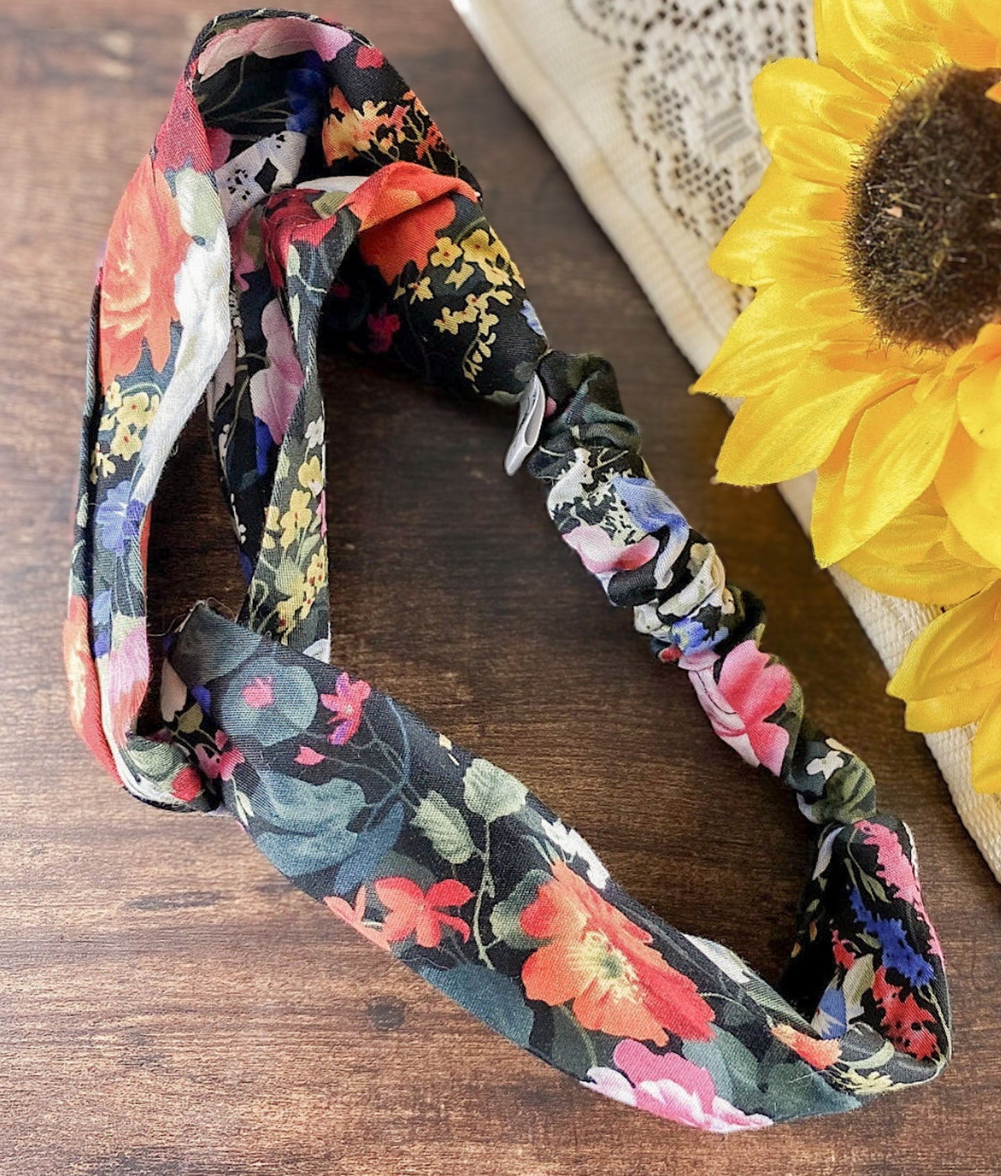 Floral patterned headband on a wooden surface with sunflowers.