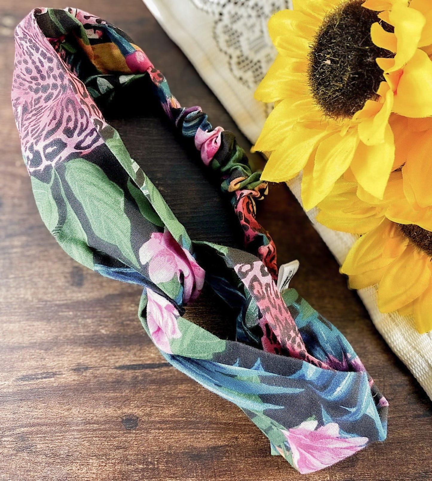 Floral patterned headband on a wooden surface with sunflowers in the background