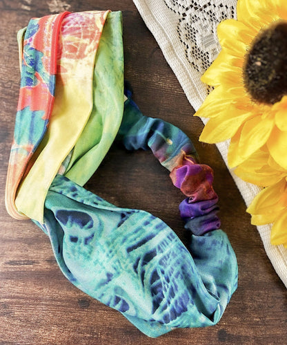 Colorful tie-dye headbands on a wooden surface with a sunflower.